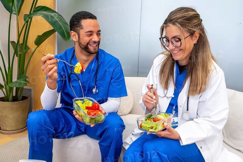 Healthcare professionals relaxing and eating fresh salads in a modern hospital setting, promoting well being, healthy habits, and nutrition among medical personnel during work