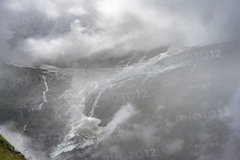 Dramatic mountain landscape covered in clouds, waterfalls and Grindelwald-Fiescherfirn glacier tongue, Bernese Alps, Bernese Oberland, Switzerland