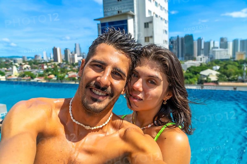 Tourists enjoying holidays in a rooftop swimming pool in cebu city, philippines, taking a selfie with cityscape in the background