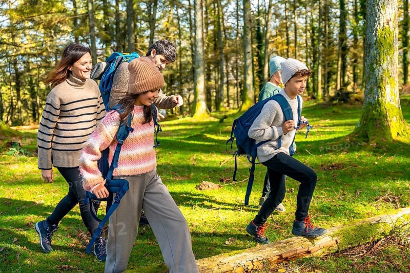 Side view full length of a happy caucasian family trekking in a green alpine forest