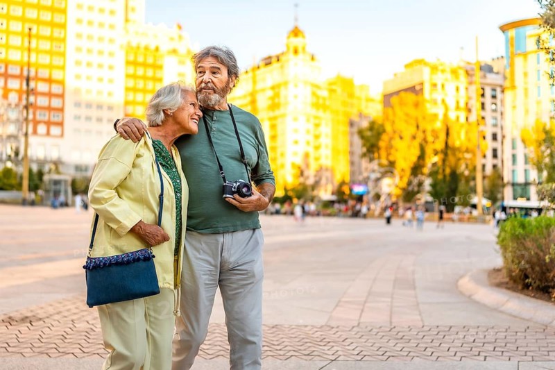 Senior couple visiting together a city holding analog camera and handbag