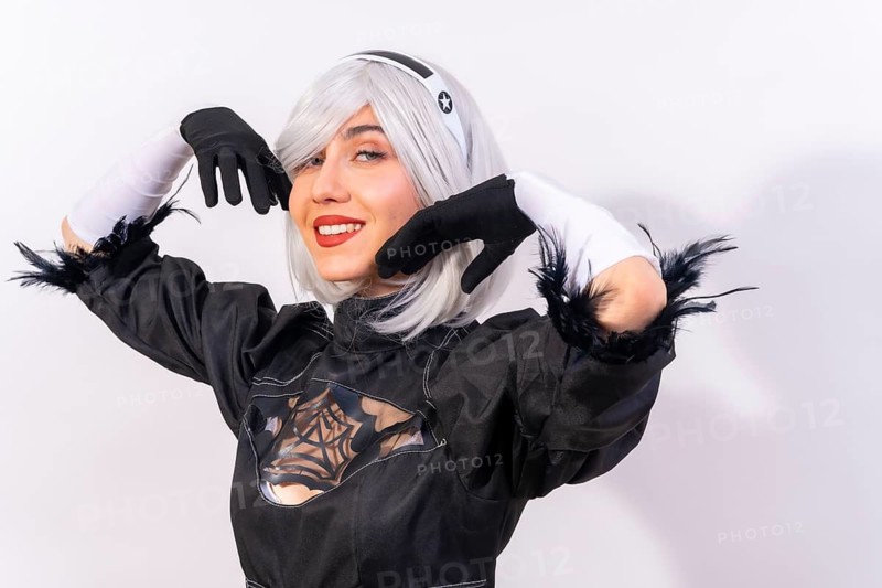 Portrait of cosplay woman in a black costume and a white wig in studio on a white background