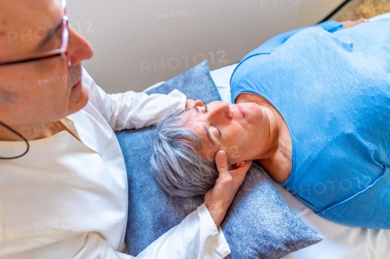 Qi gong masseur doing a massage to the head of a mature woman