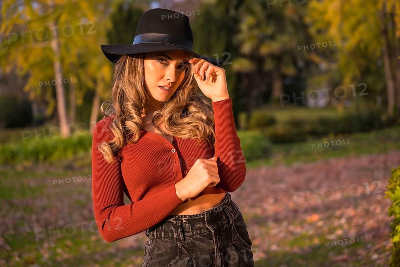 Lifestyle, portrait of a caucasian girl in a black hat at sunset in a green park