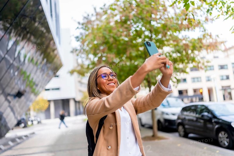 Latin woman in casual business clothes visiting a city taking photos from street views