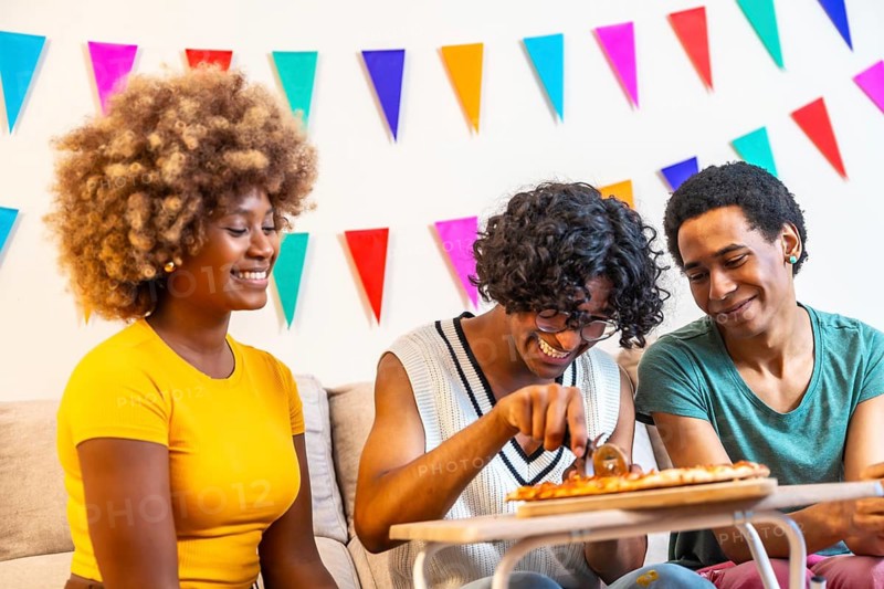 Multi-ethnic friends sharing homemade pizza during a party at home