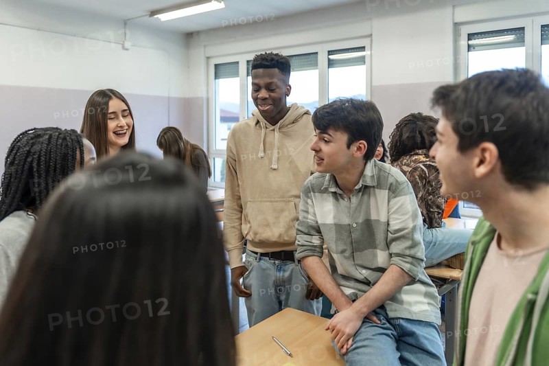 Multi ethnic group of high school students enjoying teamwork while collaborating on a school project inside a classroom