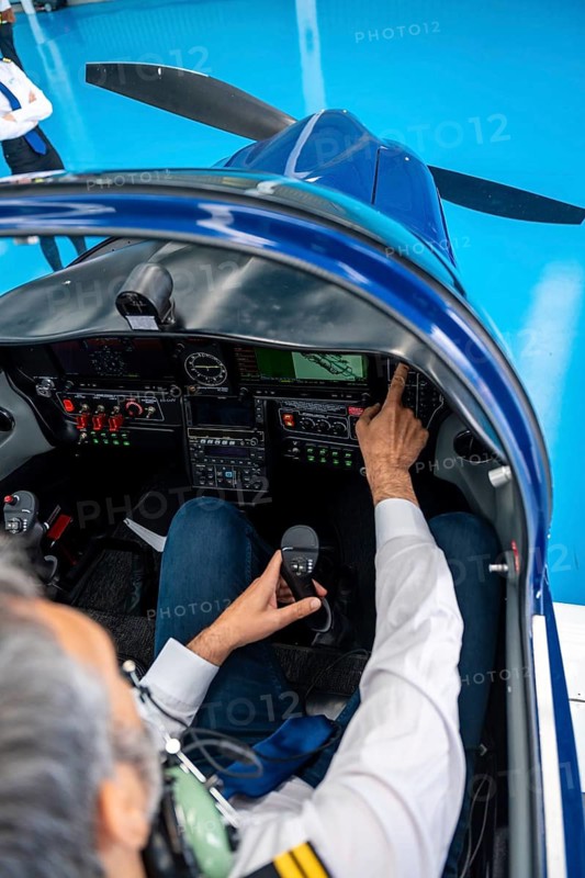 Pilot sitting in a modern light aircraft cockpit and operating controls, navigating the instrument panel and using a joy stick, demonstrating aviation technology and flight preparation