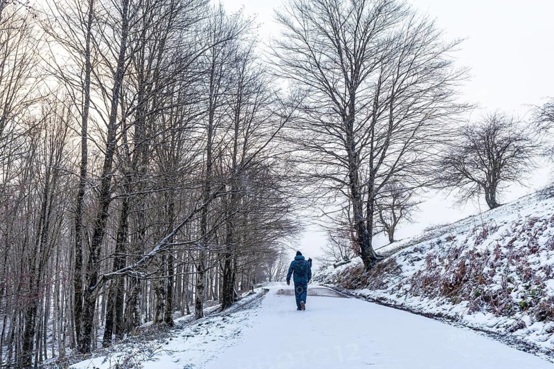 A young man walking on the path to climb Mount Aizkorri in Gipuzkoa. Snowy landscape by winter snows. Basque Country, Spain