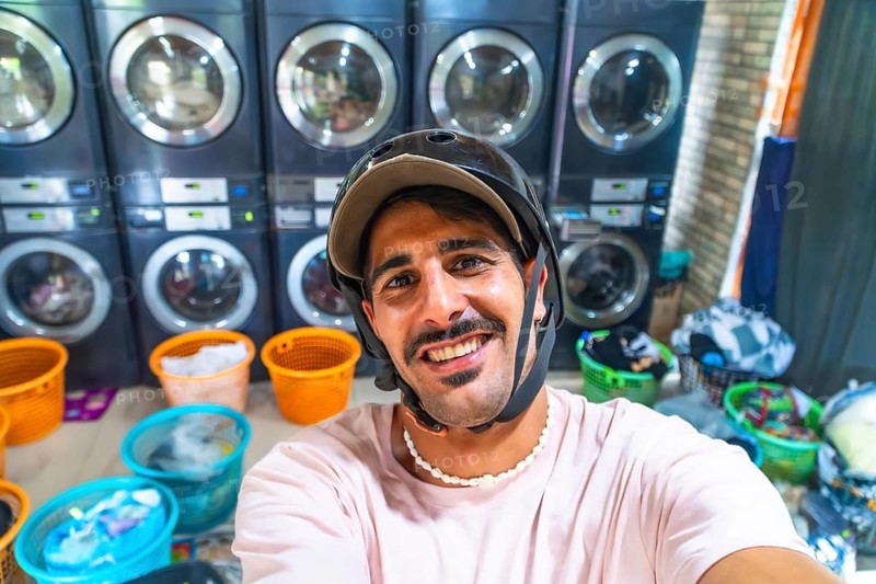 Young male tourist wearing helmet taking a selfie in a laundromat while traveling in cebu, philippines