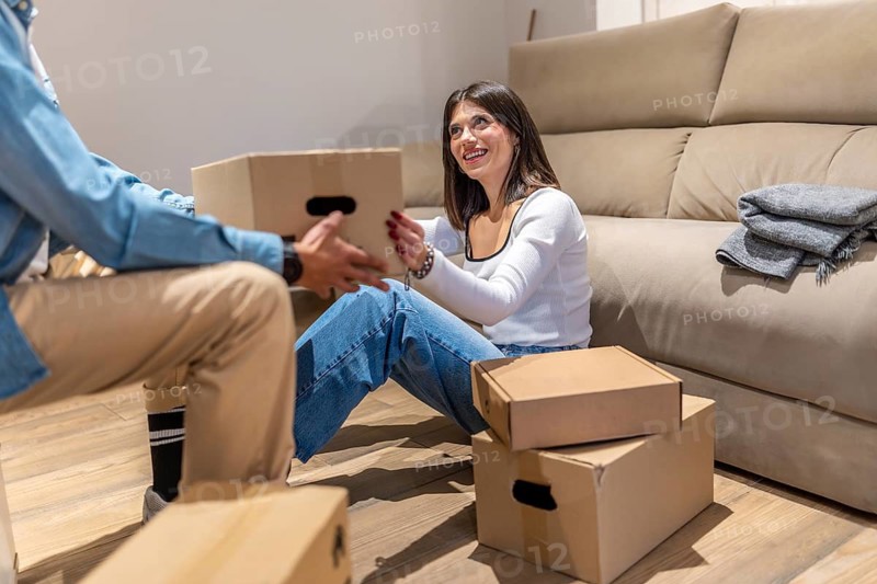 Happy couple unpacking cardboard boxes in new home living room, starting new life chapter together