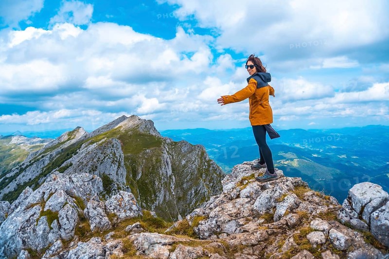 Mount Aizkorri 1523 meters, the highest in Guipúzcoa. Basque Country. Ascent through San Adrián and return through the Oltza fields. A young woman in yellow looking at the views on top