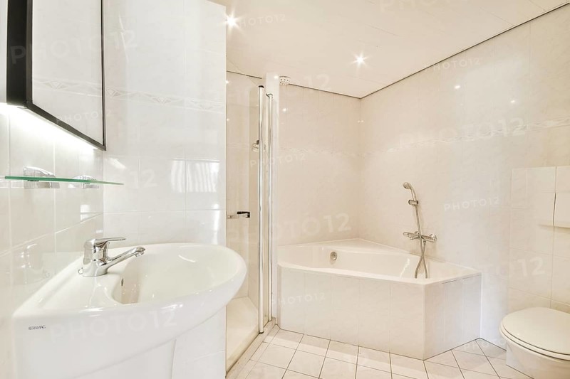A contemporary bathroom featuring a sleek shower stall, elegant bathtub, and stylish fixtures. The design emphasizes cleanliness and modern aesthetics