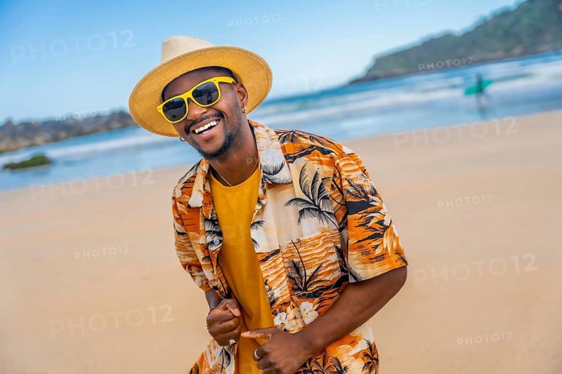 African american man in summer clothes dancing happily on the beach