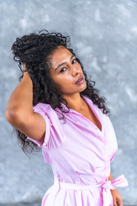 Vertical close-up portrait of a sensual latin woman with elegant pink clothes posing looking at camera