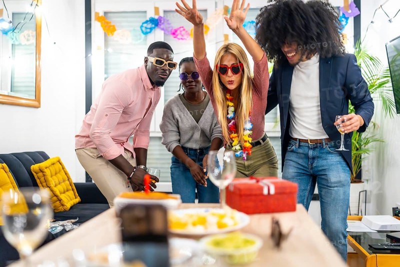 Multi-ethnic friends joking playfully having fun in a home birthday party