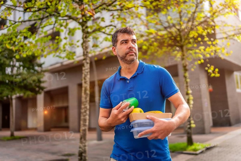 A man delivering takeaway food and beverages walking along the city