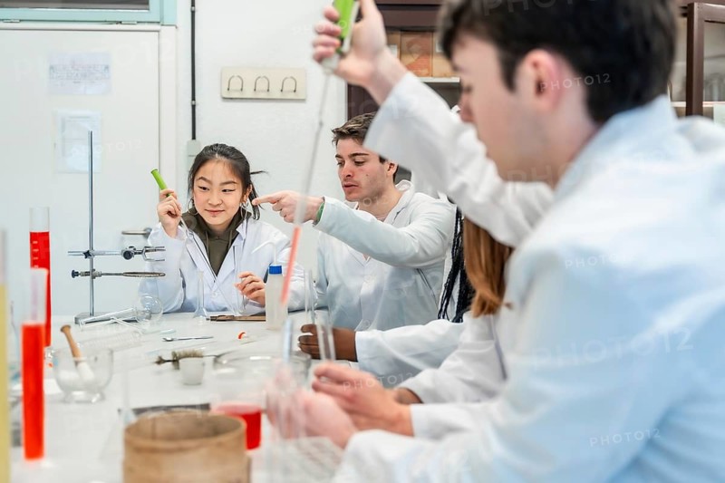 University students in lab coats conducting a chemistry experiment, collaborating and learning together