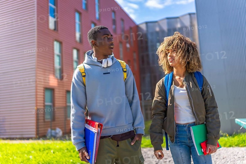 Diverse millennial students outside the university campus standing carrying notebooks, folders and rucksack