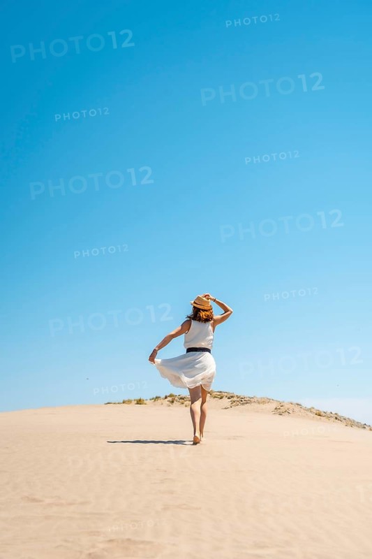 Vertical photo of a free woman in summer white dress on a dune in Cabo de Gata, Spain