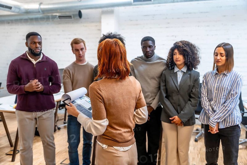Rear view of a young caucasian woman explaining project to coworking colleagues in the office