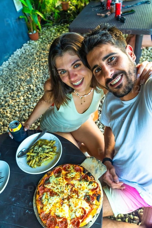 Tourists taking a selfie while having lunch with pizza and pasta in a restaurant in siargao island, philippines