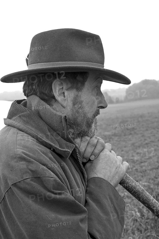 Portrait of a farmer wearing a hat, leaning on a stick while herding his cattle, black and white, Middle Franconia, Bavaria, Germany