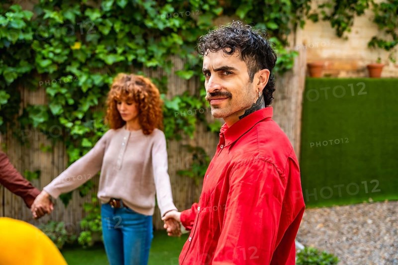 Diverse group of people holding hands in a supportive circle during an outdoor therapy session in a green garden, fostering community, trust, and connection for mental wellness