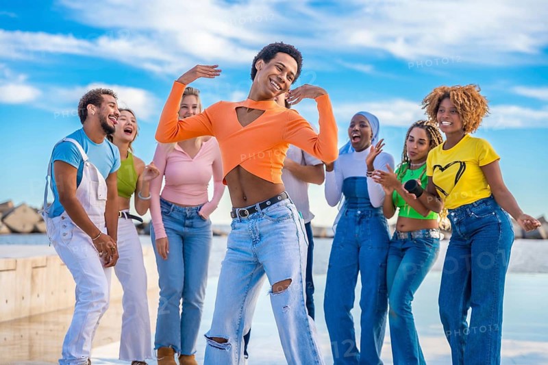 Transgender person dancing happily with multi-ethnic friends outdoors