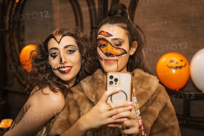 Female friends in costumes at the halloween party with friends in a disco nightclub