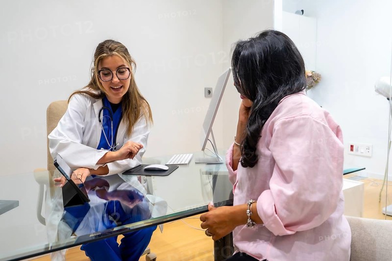 Doctor in a medical center explaining health information to a patient during a healthcare consultation, utilizing a tablet to illustrate and clarify medical concepts in a professional setting