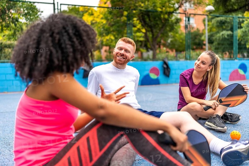 Latin woman talking with friends after playing pickelball in an outdoor court