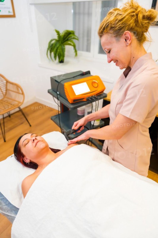 Vertical photo of a friendly female physiotherapist treating pain of a patient using Indiba technology