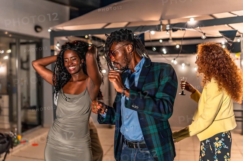 Sensual african woman dancing with friend in a night roof party with friends around
