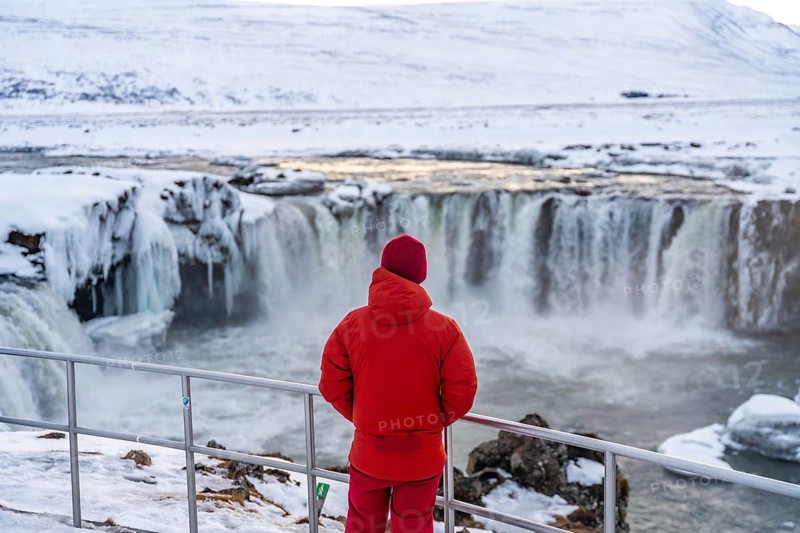A man with his back turned at the beautiful Godafoss waterfall in winter in Iceland. winter tourism