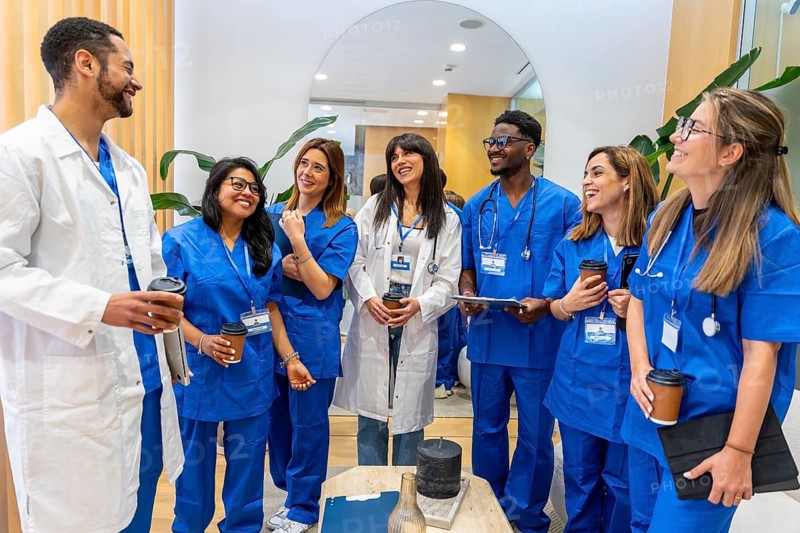 Diverse healthcare team of doctors and nurses smiling during a coffee break in a modern clinic, collaborating, exchanging ideas and showing teamwork and positive workplace energy