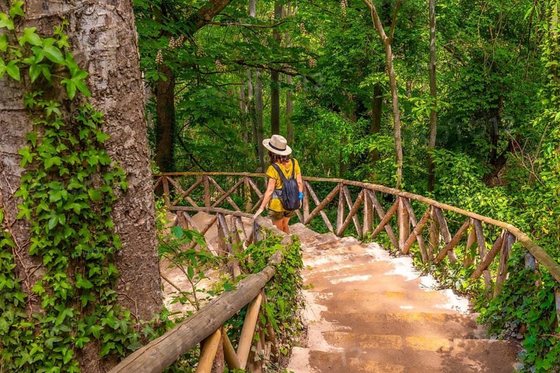 A woman with a hat walking down the stairs in the Monasterio de Piedra Natural Park, Aragon