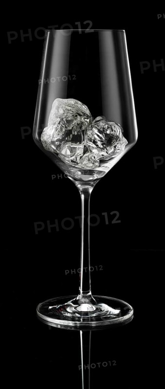 Wine glass filled with ice cube cubes in front of a black background, studio shot