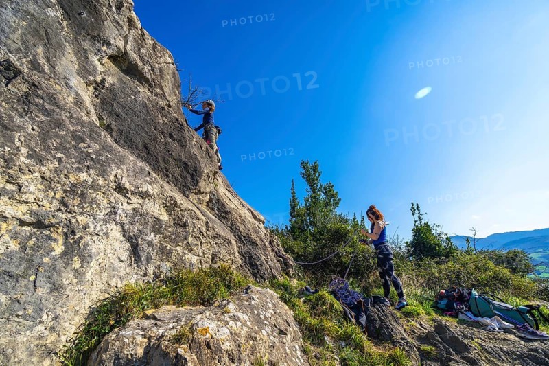 Two female rock climbers scaling a steep cliff face, enjoying a sunny day of outdoor adventure and teamwork