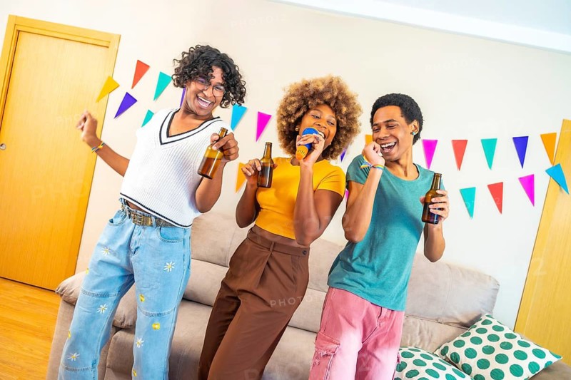 Happy multi-ethnic friends singing and dancing karaoke together during party at home