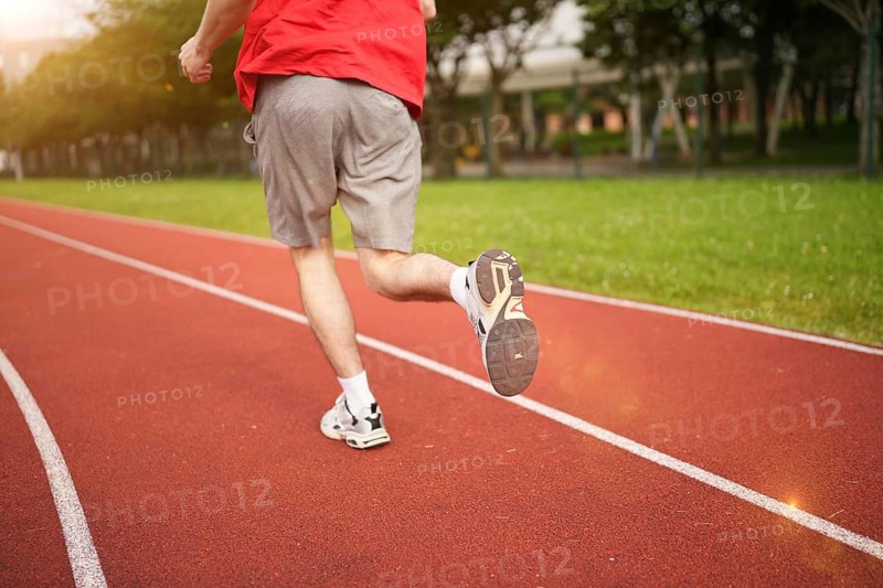 Rear view low section of a man running in a track