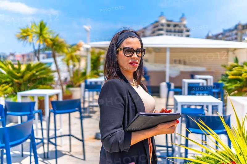 Elegant female trader using digital tablet standing on a luxury terrace