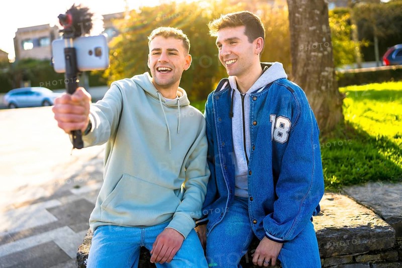 Two young content creators filming a vlog in a park, enjoying the sunny weather and sharing their experiences with online followers