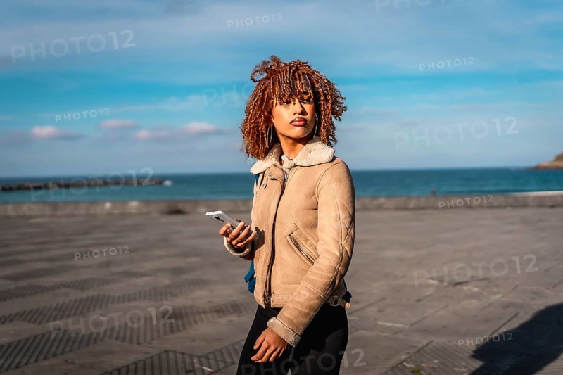 Beauty latin young woman enjoying walk in the promenade using mobile phone