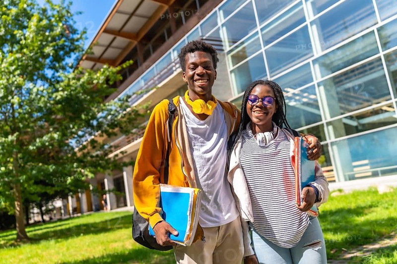 Portrait of two proud and happy african university colleagues standing outdoors in the campus