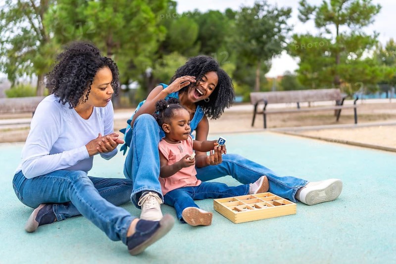 Multi-generational female african woman sitting on the park with toys for the baby