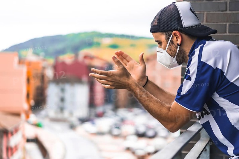 A young man in a mask applauding the toilets on the balcony at 8 in the afternoon. Pandemic coronavirus in Spain