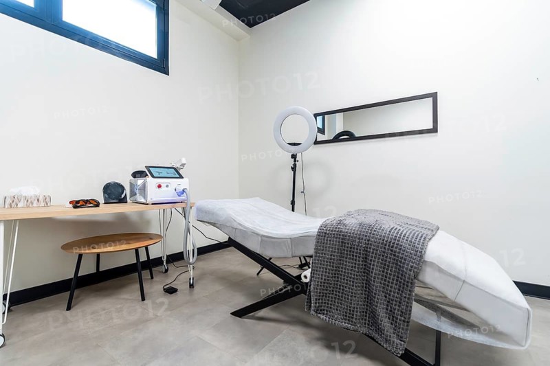 Modern clinic room featuring a laser device, protective eyewear, and a treatment bed ready for aesthetic procedures like tattoo removal or skin rejuvenation