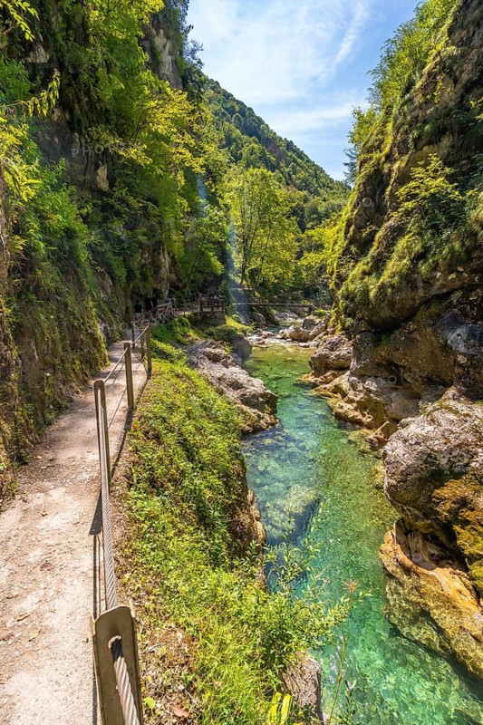 Tolmin gorge in slovenia features crystal clear turquoise water flowing through a narrow canyon, attracting summer tourists
