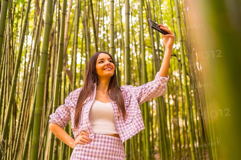 Young caucasian girl with a pink skirt in a bamboo forest. Enjoying summer vacation in a tropical climate, lifestyle of a girl doing a selfie smiling in the forest